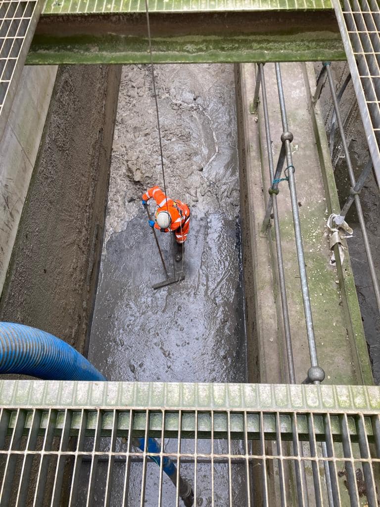 An image of a worker in a hi-vis jacket performing sludge pit emptying work.