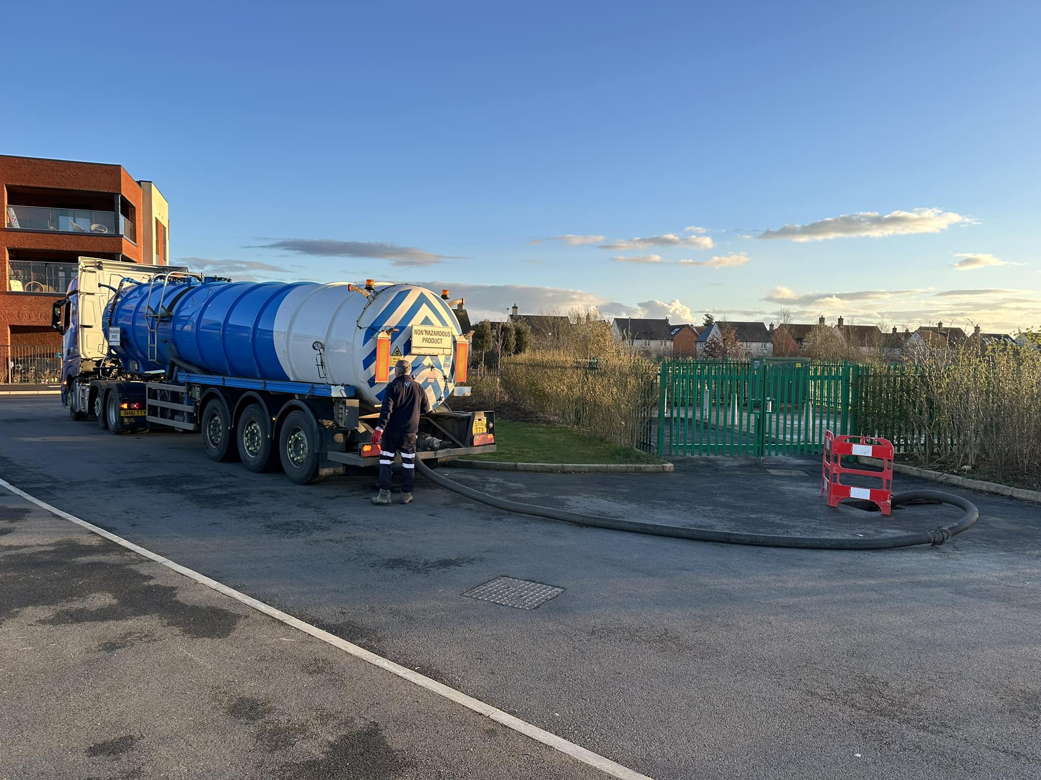 Tanker lorry working with drain on a sunny day.