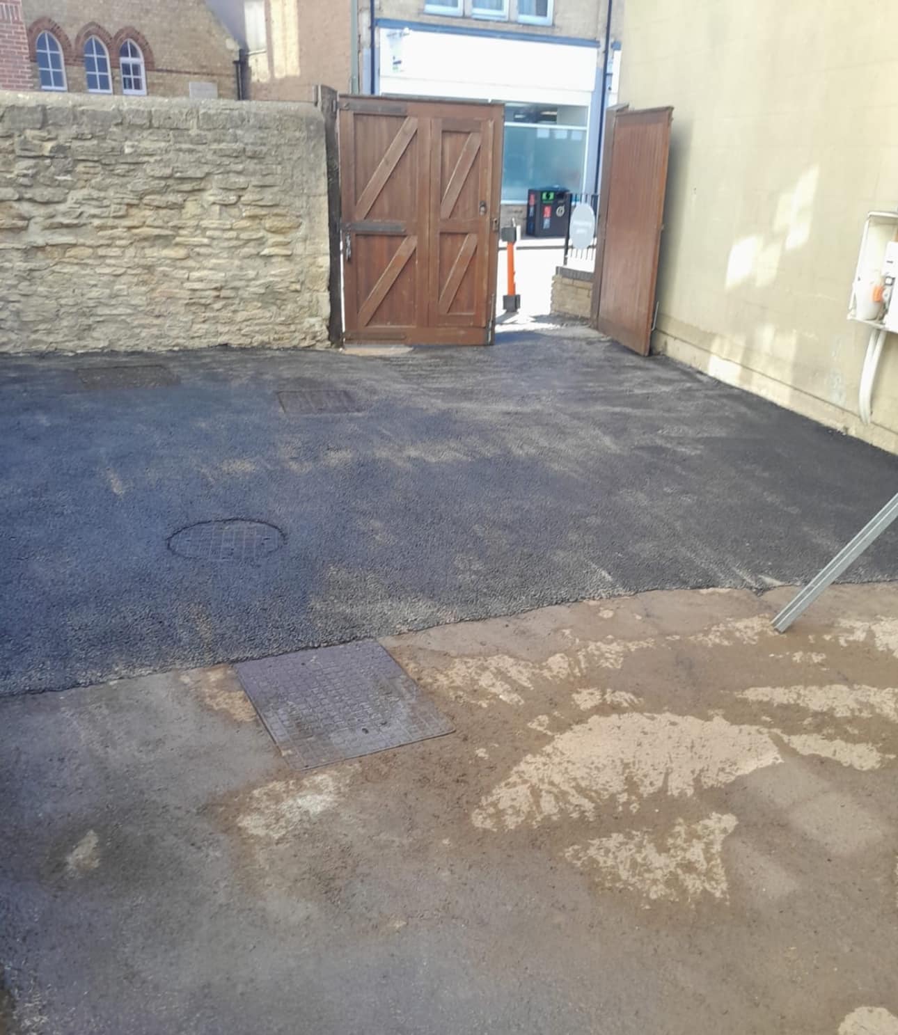 Courtyard car park with brick wall and gate.