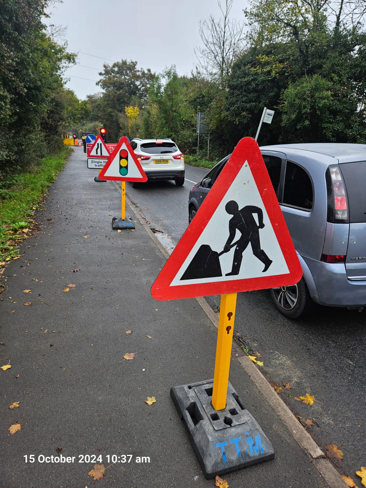 Cars waiting at traffic light by roadwork sign