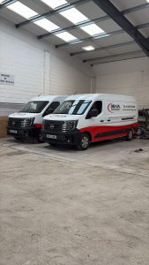 Two Drain Technology vans inside a white warehouse