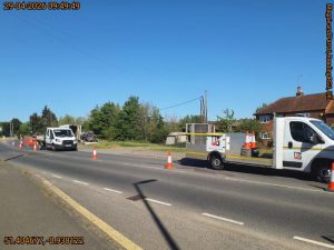 Two TTM vans inside a traffic coned lane on a road in a residential area