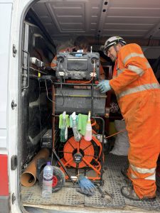 Drain Technology workers in orange overalls in the back of a van monitoring machine camera.