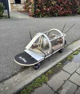 Skateboard with a tool cable tied to it on a pavement. 