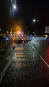 Road closure sign and traffic cones closing an exit on a roundabout. Highway maintenance van behind the cones. 