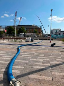 Drain tech tanker pumping in the street with tube across the ground