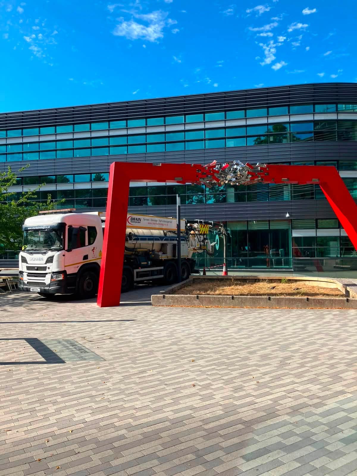 white lorry by modern building with red archway