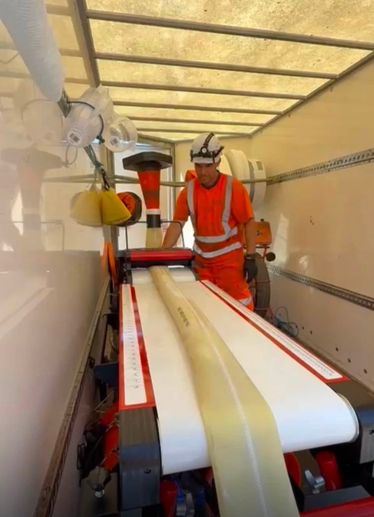 Worker in orange ppe inside a Drain Technology Pipe Rehabilitation Unit 