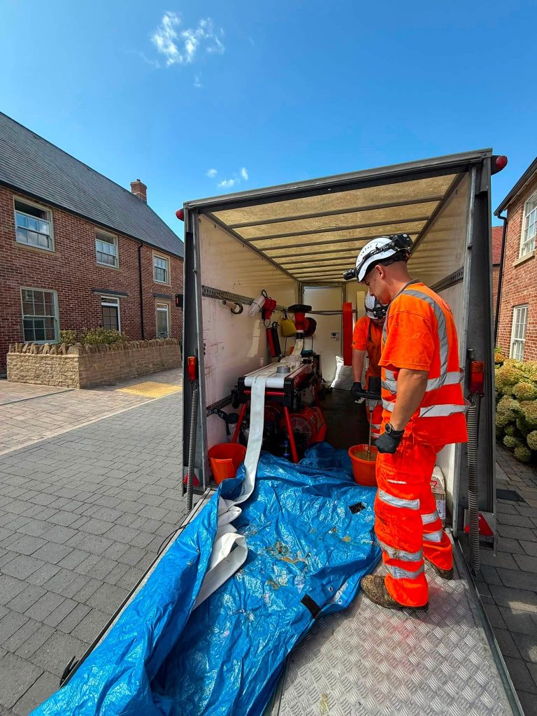 Worker in orange ppe inside a Drain Technology Pipe Rehabilitation Unit 