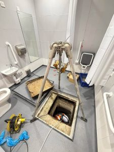 Man inside a drain in a wetroom
