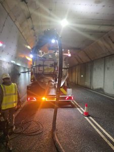 Drain technology worker and tanker being used in a dark tunnel