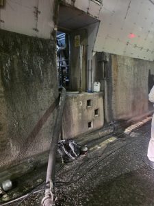 Open doorway with cables running through in a dark dirty tunnel