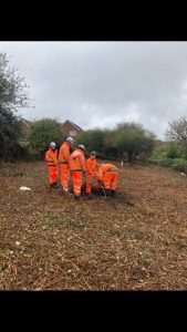 five workers in orange workwear in a field